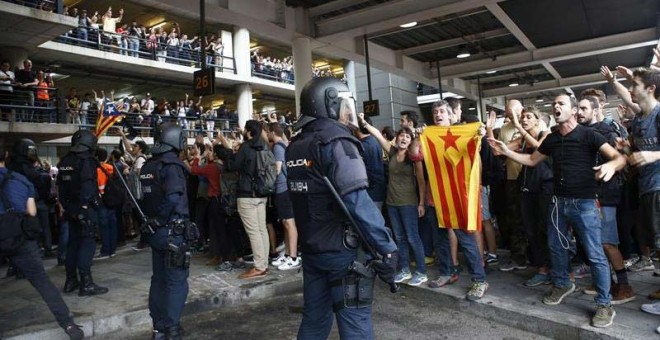 Miembros de la Policía Nacional controlan en la zona de parada de autobuses a los manifestantes independentistas que van llegando al Aeropuerto del Prat. (QUIQUE GARCÍA | EFE)