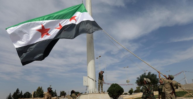 14/10/2019 - Los combatientes rebeldes sirios respaldados por Turquía alzan la bandera de la oposición siria en la ciudad fronteriza de Tel Abyad. REUTERS / Khalil Ashawi