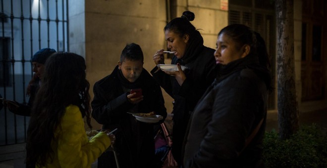 Una madre, solicitante de asilo colombiana, cena gracias a la ayuda de la Red de Solidad Popular, junto a sus tres hijos menores, en la puerta del Samur Social de Madrid-. JAIRO VARGAS
