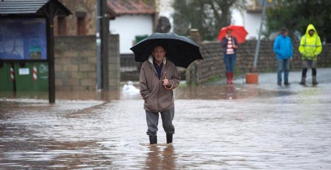 23/10/2019.- Un hombre camina por el agua que inunda Virgen de la Peña en Cantabria. EFE/Pedro Puente Hoyos