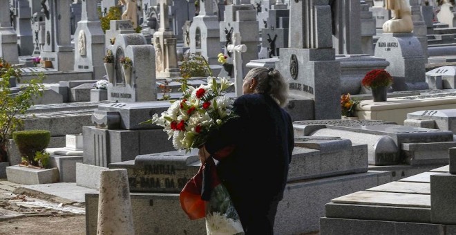 Una mujer con flores visita el madrileño cementerio de La Almudena, el Día de Difuntos. EFE/Paco Campos