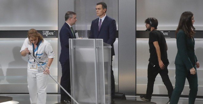 04/11/2019 - Una limpiadora antes de comenzar el debate. Al fondo, el presidente del Gobierno en funciones, Pedro Sánchez. / EFE
