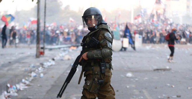 Un miembro de los Carabineros, el cuerpo policial de Chile, frente a los manifestantes en la céntrica Plaza Italia de Santiago. EFE/Alberto Valdés