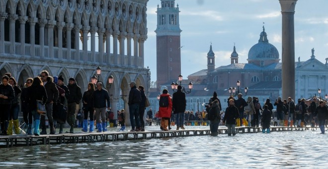 14/11/2019.- La gente camina por una pasarela improvisada sobre la Plaza de San Marcos inundada, Venecia, Italia. REUTERS / Manuel Silvestri
