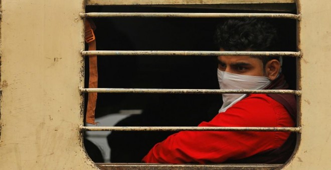 Un joven, con la nariz y la boca cubiertas para protegerse de la contaminación, en un tren en Nueva Delhi. REUTERS/Anushree Fadnavis