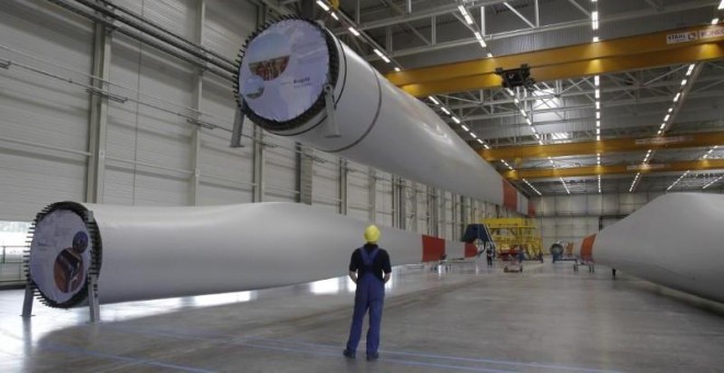 Un trabajador mira un ala que está siendo levantada mecánicamente en la fábrica de turbinas eólicas de Nordex en Rostock. REUTERS / Tobias Schwarz