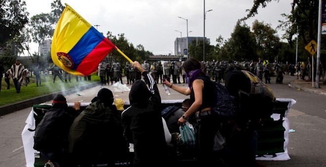 21/11/2019.- Un grupo de jóvenes se cubre frente a miembros de la Policía durante una manifestación en Bogotá (Colombia). / EFE - JUAN ZARAMA