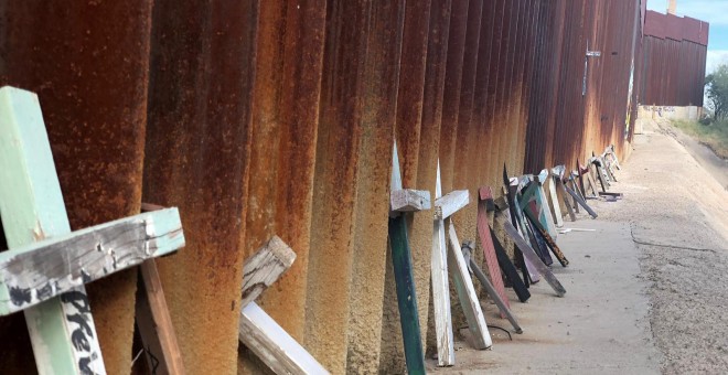 Apoyadas sobre el muro fronterizo en Nogales (México) hay decenas de cruces de madera en honor a los migrantes que perecieron tratando de alcanzar EE.UU. con vida. / Aitana Vargas