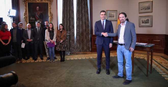 El presidente del Gobierno en funciones, Pedro Sánchez y el líder de Podemos, Pablo Iglesias, se estrechan la mano en el Congreso de los Diputados tras firmar el principio de acuerdo para compartir un gobierno de coalición tras las elecciones generales de