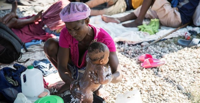 Una mujer baña a su bebé en un campamento en Puerto Príncipe, Haití. REUTERS