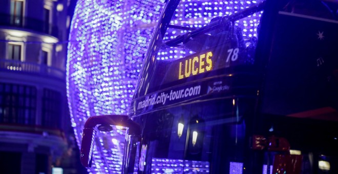 22/11/2019- Un autobús de turistas el que se lee en un panel luminoso 'Luces', pasa junto a una bola gigante de Navidad encendida en Madrid. / EUROPA PRESS