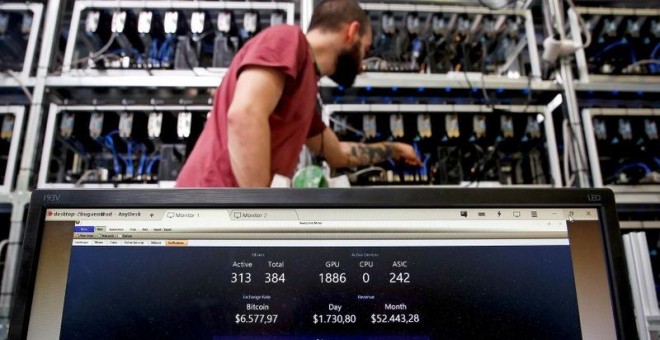 Un empleado trabaja en el ordenador de minería de Bitcoin mientras  una pantalla de PC muestra las fluctuaciones de la criptomoneda, en Florencia, Italia. REUTERS/Alessandro Bianchi