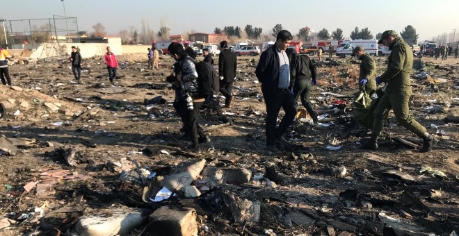 Miembros del equipo de rescate con personas revisan los escombros de un accidente aéreo perteneciente a Ukraine International Airlines después del despegue del aeropuerto iraní Imam Khomeini, en las afueras de Teherán, Irán, 8 de enero de 2020. Nazanin Ta