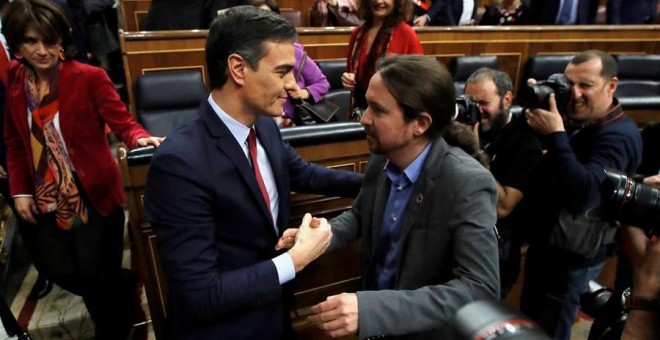El líder de Unidas Podemos, Pablo Iglesias (d), felicita a Pedro Sánchez, quien logró este martes la confianza del Congreso para un nuevo mandato como presidente del Gobierno, al lograr una estrecha mayoría de 167 votos a favor, 165 en contra y 18 absten