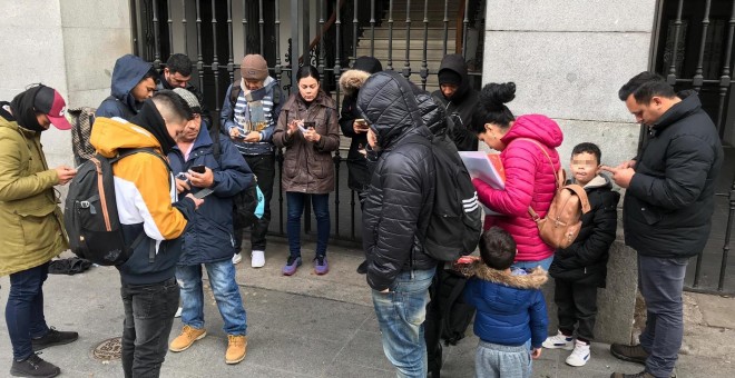 Varios solicitantes de asilo intentan reservar su cita previa de extranjería para acceder al sistema de acogida, en la puerta del Samur Social de Madrid.- RSP