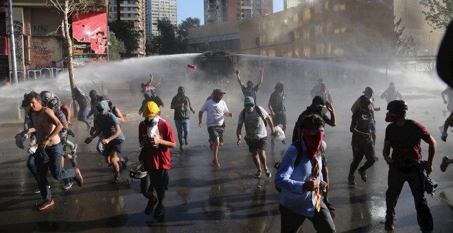 Un grupo de manifestantes huyen del camión lanza agua de la policía antidisturbios, durante una protesta contra el Gobierno del presidente Sebastián Piñera, en la plaza Italia de Santiago (Chile). - EFE/Elvis González