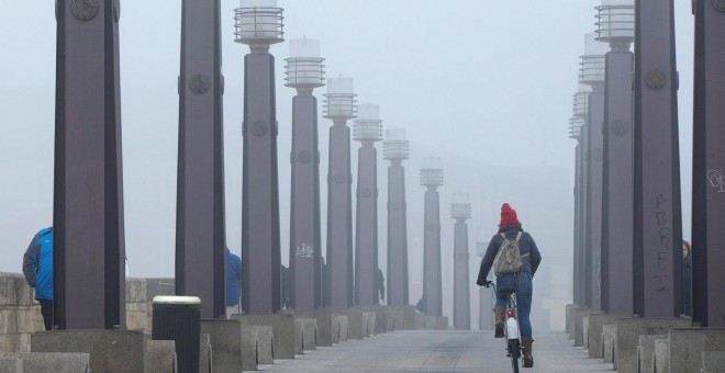 13/01/2020.- Una joven atraviesa en bicicleta el Puente de Piedra sobre el río Ebro a su paso por Zaragoza este lunes. / EFE - JAVIER CEBOLLADA