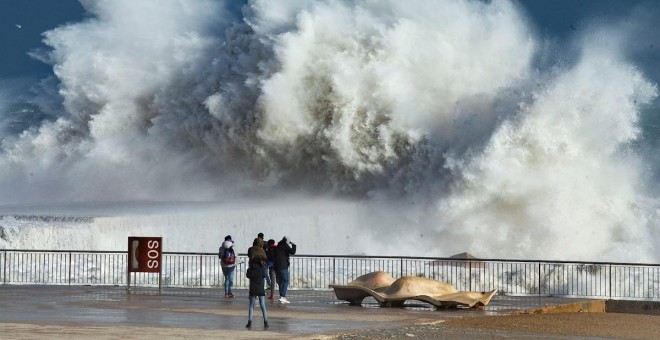 20/01/2020.- Varias personas observan las grandes olas en la playa de la Barceloneta, en Barcelona, este lunes, durante el fuerte temporal de Levante que azota Cataluña y que deja registros históricos de oleaje, viento y nieve, como la ola de 12 metros re