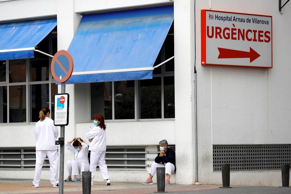 Personal sanitario del Hospital Arnau de Vilanova descansa unos minutos ante la puerta de urgencias, hoy durante el sexto día del estado de alarma decretado por el Gobierno.EFE/ Manuel Bruque