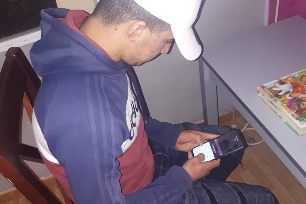 Ahmed, en casa, usando el teléfono para conectarse con su familia