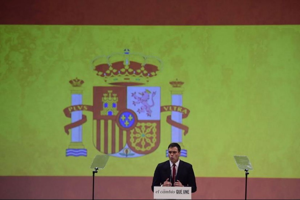 Pedro Sánchez, junto a una gran bandera rojigualda. EFE