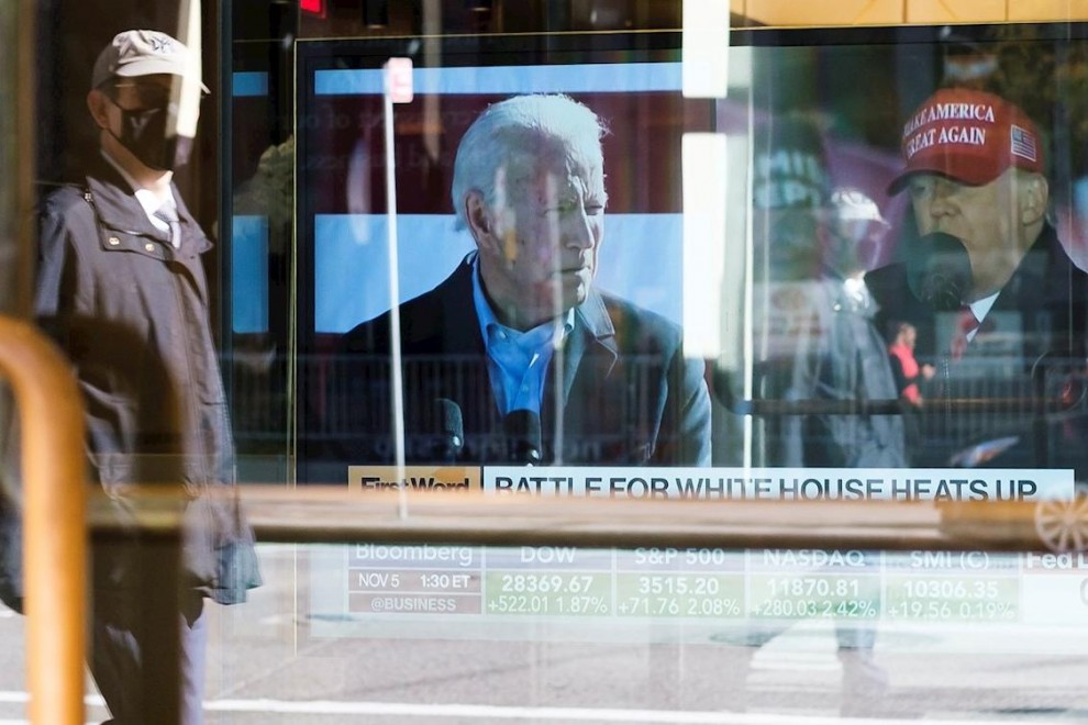 Un hombre pasa junto a un escaparate en Nueva York con un informativo sobre la disputa electoral entre Biden y Trump.