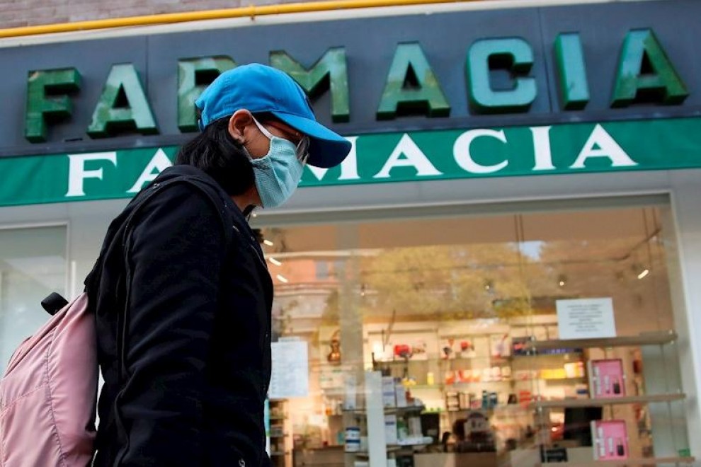 Imagen de archivo de una viandante, protegida con guantes y mascarilla, pasa por delante de una farmacia.