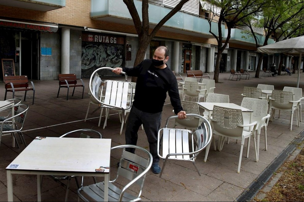 Un camarero prepara la terraza del restaurante donde trabaja en L'Hospitalet de Llobregat para atender a sus clientes en el turno de 13:00h a 16:30h, uno de los dos horarios permitidos para la restauración.
