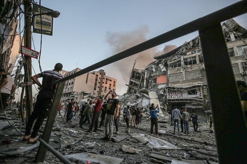 Un grupo de palestinos inspeccionan los restos de una torre destruida por un bombardeo israelí.