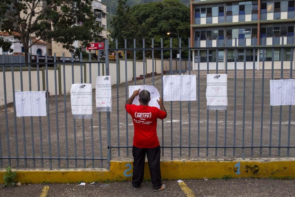 Un hombre busca su nombre en las hojas del padrón electoral a la entrada de un colegio electoral durante las elecciones regionales y municipales en Caracas, el 21 de noviembre de 2021.