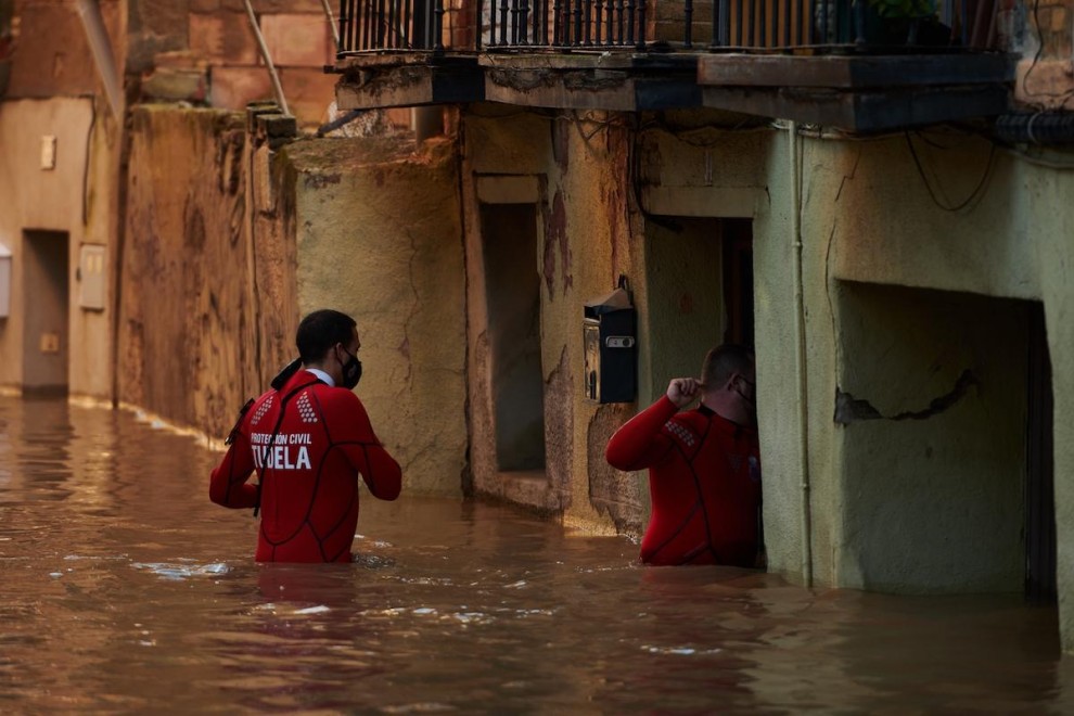 Trabajadores de Protección Civil caminan por una calle inundada, a 12 de diciembre de 2021, en Tudela, Navarra.