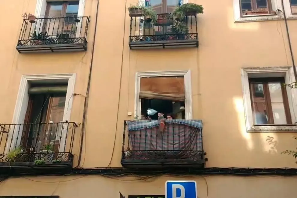 Marina, de 94 años, saluda desde su balcón a los colectivos vecinales que han ayudado a frenar su desahucio.