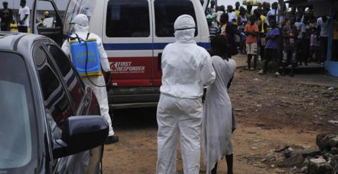 Un sanitario rocía una solución de cloro a una mujer sospechosa de estar infectada por el virus de ebola en Liberia.