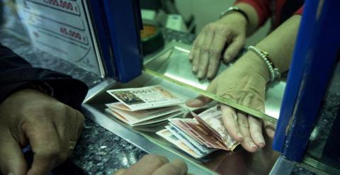 Un hombre compra varios décimos en la administración de lotería Bello, situada en la plaza del Ayuntamiento de Valencia, aprovechando los últimos días antes del sorteo extraordinario de Navidad que se celebra este lunes.