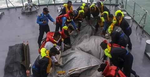 Fotografía facilitada por la Armada de Malasia que muestra a miembros del buque de la Armada Malasia 'Lekir' recuperando una pieza del Airbus 320-200 de AirAsia siniestrado el domingo en el mar de Java con 162 personas a bordo, frente a la costa de Pangka