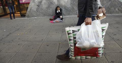 Un sin techo, en la puerta de un centro comercial en temporada de rebajas. REUTERS