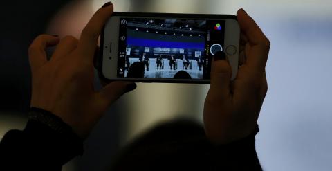 Un asistente a las conferencias del foro de Davos toma una foto con su smartphone. REUTERS/Ruben Sprich