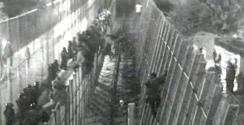 Imagen del vídeo donde se observa a los 400 inmigrantes subsaharianos en la valla. EFE