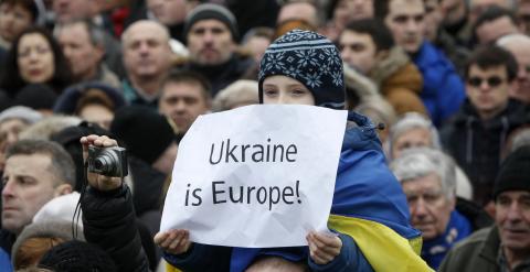 Un niño, sobre los hombros de un adulto, sostiene una pancarta en la que se lee 'Ucrania en Europa', durante la llamada Marcha de la Dignidad, para celebrar el aniversario del levantamiento de la plaza de Maidan, en Kiev. REUTERS/Valentyn Ogirenko