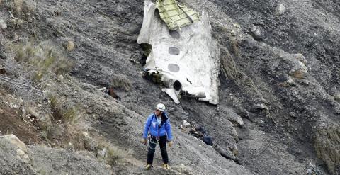 Un miembro de los servicios de rescate camina al lado del mayor un tramo de fuselaje del avión siniestrado, en el que se aprecian tres ventanillas, entre millones de fragmentos del aparato esparcidos por una amplia área de alta montaña en los Alpes france