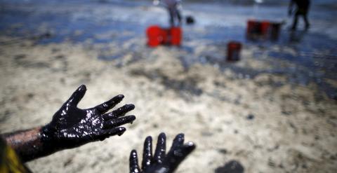 Varios voluntarios limpian una de las playas afectadas por el vertido. / LUCY NICHOLSON (REUTERS)