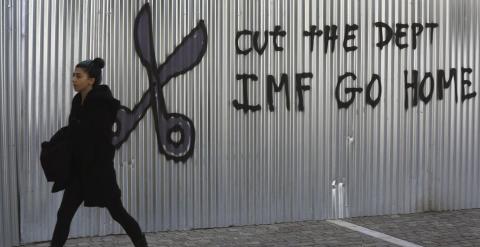 Una mujer pasea por el centro de Atenas junto a una pintura en contra del FMI.- REUTERS