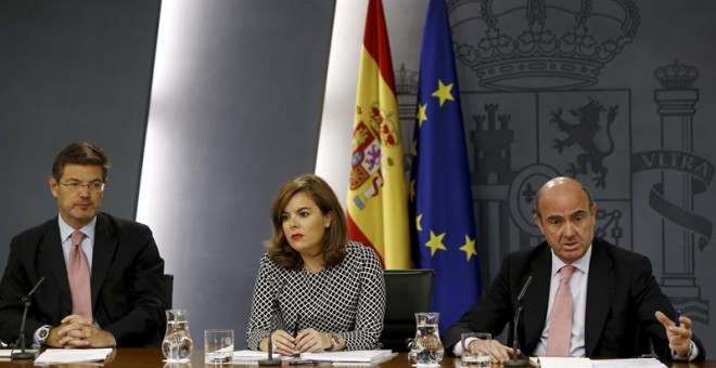 La vicepresidenta del Gobierno Soraya Sáenz de Santamaría junto a los ministros de Justicia, Rafael Catalá, (iz),y Economía, Luis de Guindos. /EFE