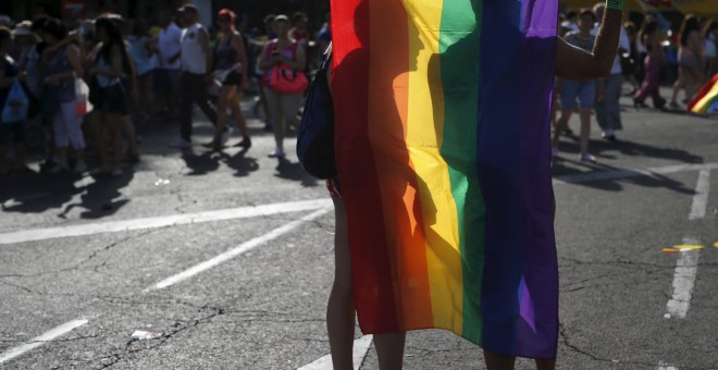 Dos manifestantes se cubren con la bandera arcoíris durante la marcha del Orgullo. REUTERS/Javier Barbancho