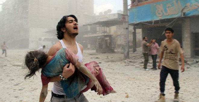 Imagen de un joven sirio cargando una niña herida tras un atentado. EFE