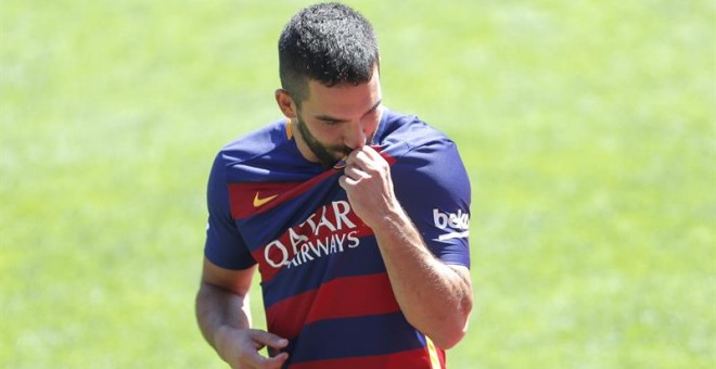 Arda Turan besa el escudo del Barça al ser presentado en el Camp Nou. /EFE