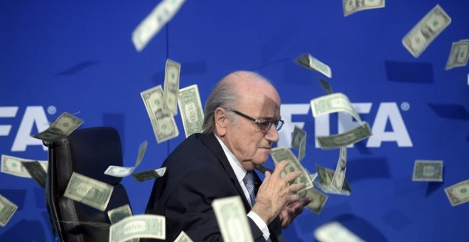 El presidente de la FIFA, Joseph Blatter, bajo una lluvia de billetes que le lanzó el humorista británico Simon Brockin.- ENNIO LEANZA (EFE)