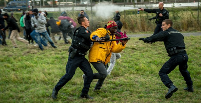 Gendarmes franceses tratan de detener inmigrantes que intentan cruzar el Eurotunel camino a Inglaterra.- PHILIPPE HUGUEN (AFP)