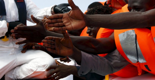 Un grupo de inmigrantes extiende la mano a la espera de ser rescatados frente a la costa de Libia. REUTERS/Darrin Zammit Lupi