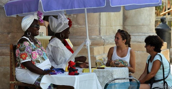 Dos turistas consultan su futuro con cartománticas en La Habana. Toparse con visitantes de Estados Unidos por La Habana es cada vez más habitual, atraídos por los coches antiguos que todavía circulan por su calles y sus edificaciones anteriores a la Revol